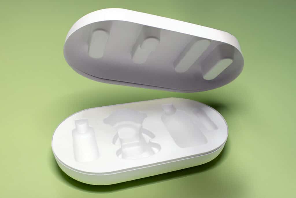 Molded pulp packaging box with lid and custom compartments for bottles and a central product, shown on a green background.
