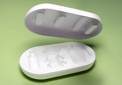 Molded pulp packaging box with lid and custom compartments for bottles and a central product, shown on a green background.
